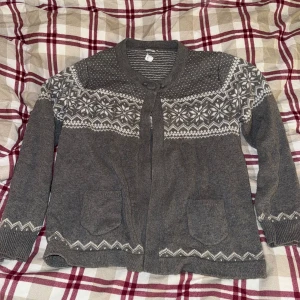 Grå stickad kofta med mönster - Klassisk! Mysig grå stickad kofta med ett snyggt vitt mönster över axlarna och längs ärmarna. Perfekt för kyliga dagar, med praktiska fickor framtill Passar både till vardags och mysiga hemmakvällar.💞