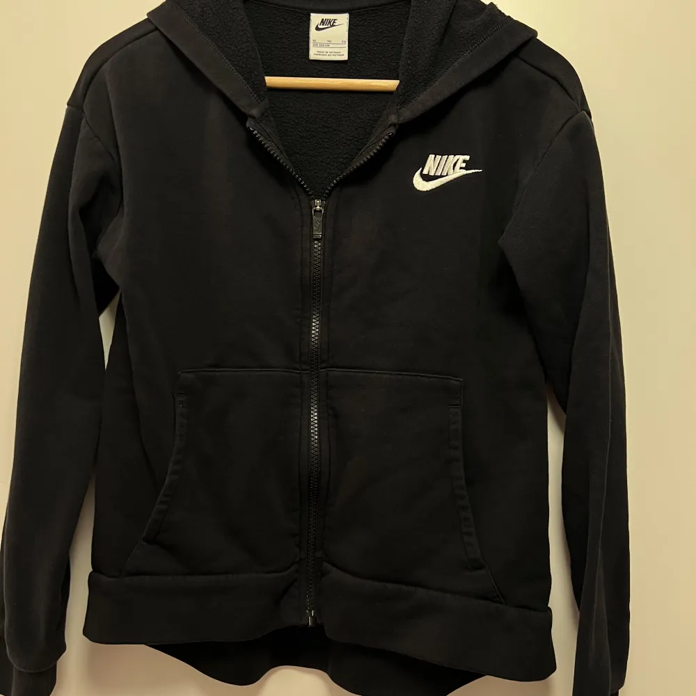 Säljer en svart hoodie från Nike i mycket bra skick. Den har en dragkedja framtill och en mysig fleecefodrad insida. Perfekt för höst och vinter! Den har långa ärmar och en klassisk Nike-logga på bröstet. Superbekväm och stilren för vardagsbruk. STOLEK 156 - 166. Jackor.