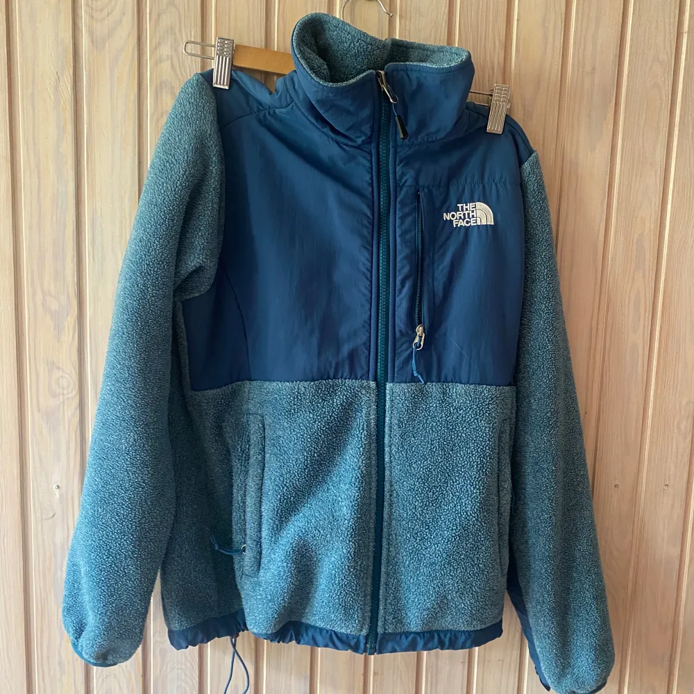 Säljer en supermysig blå fleecejacka från The North Face. Den har en dragkedja framtill och en hög krage för extra värme. Perfekt för kyliga höst- och vinterdagar. Jackan har en normal passform och är i mycket bra skick. Perfekt för både vardag och friluftsliv!. Jackor.