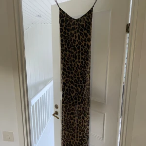 Leopardklänning - Långklänning i storlek 34 med öppen rygg och korsade band samt v-ritning ifram Från gina tricot men säljs inte längre