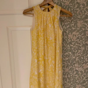 Gul finklänning - Gul mönsterklänning, med rosettknyte i ryggen, storlek 32 ifrån H&M! Använd vid ett fåtal tillfällen.