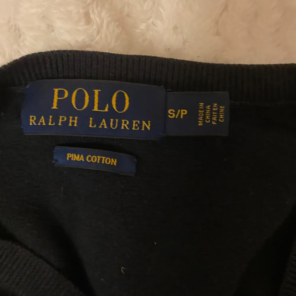 Säljer en stilren svart tröja från Polo Ralph Lauren i mjuk pima bomull. Tröjan har en klassisk v-ringning och den ikoniska röda loggan på bröstet. Perfekt för både vardag och fest!. Hoodies.