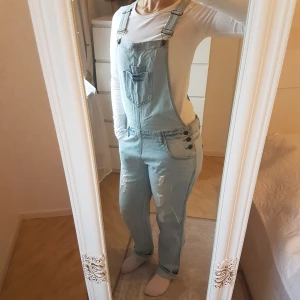 Primark, jeans-hängselbyxor - Sparsamt använda, från Primark i London. Inga tecken på anv. Lågmidjad, rak modell med slitningar. Fin detalj är fickor av rosa foder, som skiner igenom lite i slitningarna högst upp. Är 167cm, för referens. ~ STOR rensning & erbj i min shop ~