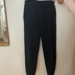 Svarta mjukisbyxor från Lindex - Säljer ett par svarta mjukisbyxor från Lindex i storlek 146/152. De är superbekväma med en elastisk midja och dragsko för perfekt passform. Perfekta för en avslappnad dag hemma eller en snabb tur till affären. 🖤