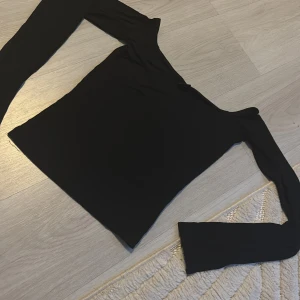 Svart långärmad topp  - Snygg svart långärmad topp med en stilren design. Perfekt för en minimalistisk look. Tillverkad i ett mjukt och bekvämt material.