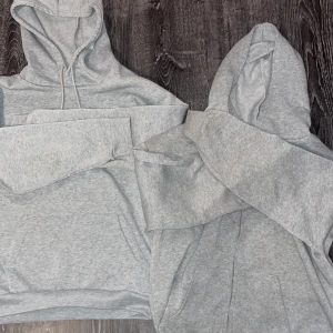 Grå hoodie - Säljer en klassisk grå hoodie med justerbar huva och rymlig magficka. Perfekt för en avslappnad stil och passar till de flesta tillfällen. Mjuk och bekväm att bära. Ena har en dragkedja.