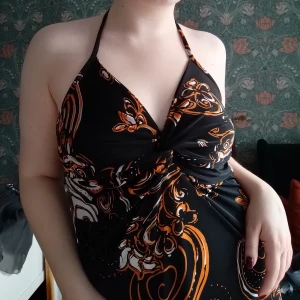 Svart halterneck-klänning med mönster - Vintage svart halterneck-klänning med ett coolt unikt mönster i orange och vitt. Klänningen har en twisdesign framtill. Superskön och sval🩷