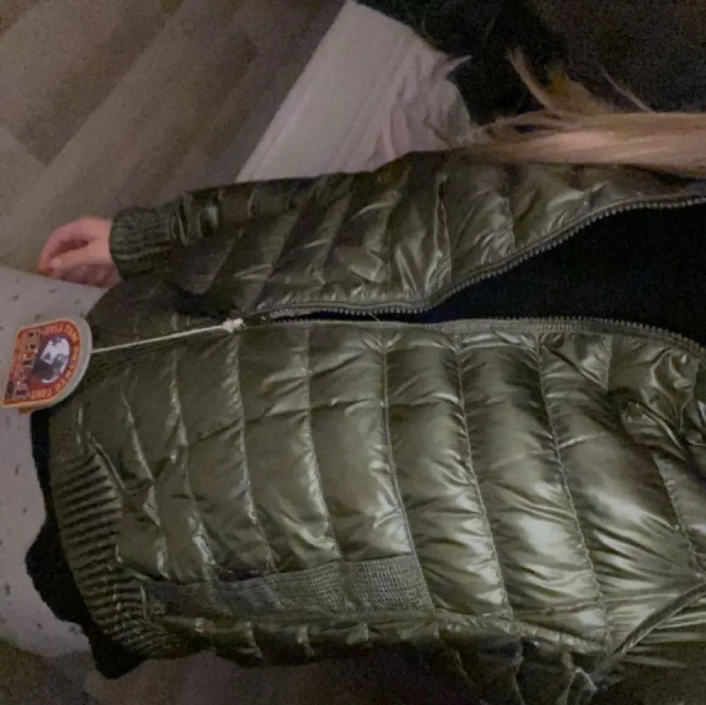 Snygg olivgrön pufferjacka från Parajumpers med dragkedja och ribbade muddar. Perfekt för kyliga dagar med sin quiltade design och långa ärmar. Jackan kan användas ut och in, då den är dubbeljacka, om du vänder den ut och in så är färgen på jackan åt de rosa hållet ( skriv för mer bilder) i bra skick så jag bara använt få gånger, har orginal galgen till. Skulle säga att den sitter som en xs . Takit.