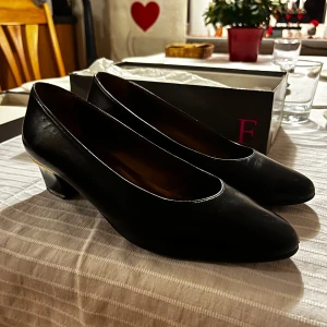 Svarta pumps med klack - Eleganta svarta pumps med låg klack och spetsig tå. Perfekta för en stilren look. Skorna har en klassisk design som passar till många olika tillfällen. Äkta skinn. Från märket Fransi Copenhagen. Nypris 625. 