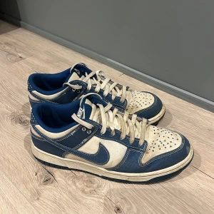 Nike Dunk sneakers i blått och beige - Snygga Nike Dunk sneakers i en cool kombination av blått och beige. Skorna har klassisk snörning och en perforerad tå för extra ventilation. Perfekta för en avslappnad stil.