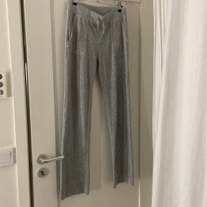 Grå mjukisbyxor från Juicy Couture - Snygga grå mjukisbyxor från Juicy Couture med snörning i midjan och fickor både fram och bak. Perfekta för en avslappnad stil.