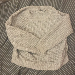 Beige stickad tröja från 157 - Mysig beige stickad tröja från 157. Perfekt för kyliga dagar med sin varma och bekväma design. Tröjan har långa ärmar och en rund halsringning.