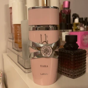 Lattafa Yara Eau de Parfum 100ml - Upptäck Lattafa Yara, en elegant parfym i en stilren rosa flaska med silverdetaljer. Doften är en härlig mix av söta och pudriga toner med inslag av vanilj, tropiska frukter och blommor. Perfekt för dig som älskar en fräsch och fruktig doft med en touch av citrus och mysk. Det är ungefär 70 ml kvar i flaskan, säljer då jag inte använder den ofta.