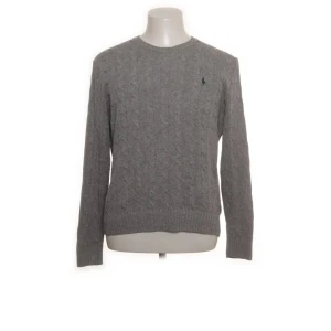 Polo Ralph Lauren cable knit grey - Snygg grå stickad tröja från Polo Ralph Lauren i storlek M. Tröjan har ett diskret mönster och är tillverkad i 100% silke, vilket ger en lyxig känsla. Perfekt för kyligare dagar med sin långärmade design. Otroligt skön att ha på sig och man får många komplimanger. Passar till många olika outfits och är enkel att matcha. Original priset är ungefär 2500kr.