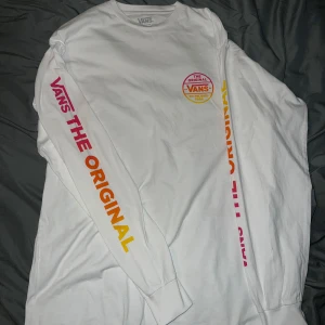 Vit långärmad tröja från Vans - Säljer en vit långärmad tröja från Vans med tryck på bröstet och ärmen. Texten 'THE ORIGINAL' i rött och orange pryder ärmen.