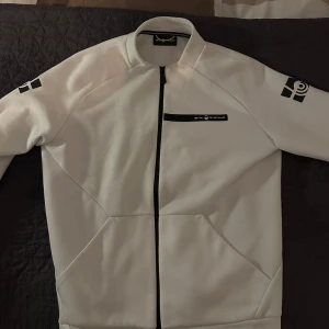 Sail Racing zip hoodie  - Vit sail racing zip hoodie i limitirat exemplar. Sparsamt använd skick 9/10. Storlek S/M. Nypris runt 1500kr Perfekr nu till denna årstid men passar till vår och sena sommarkvällar med.