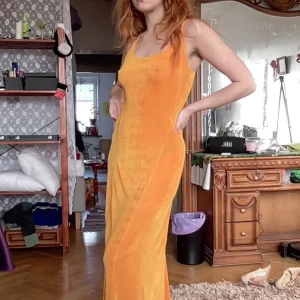 Orange långklänning i tungt skimrande tyg - Snygg orange långklänning i tungt skimrande typ med bekväm och stretchig passform.  Längd: 141cm Ärm: 34cm