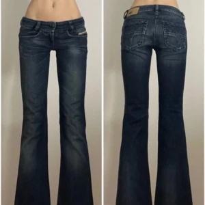 Blå bootcut jeans från Diesel - Snygga blå bootcut jeans från Diesel med klassisk femficksdesign och låg midja. Jeansen har en lätt slitning för en trendig look och en logotyp på bakfickan. Perfekta för en avslappnad stil. Storleken står på bild i W och L💕💕 midjemåttet: 37cm. Innerbenslängden: 70cm. Bredd längste ner: 22cm. Höjd av midja: 19cm💕💕 De är pytte lite slitet under dragkedjan (ett litet hål) men man ser inte de!💕💕