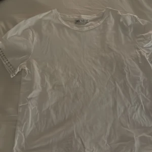 Vit t-shirt från Zara med spetsdetaljer - Säljer en stilren vit t-shirt från Zara med korta ärmar och snygga spetsdetaljer längs ärmarna. Tröjan är i st S men passar även XS!🫶🏻