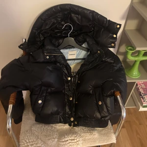 Svart bomber dunjacka från Sandro - Snygg svart dunjacka från Sandro i stl 36. Jackan är varm och skön, har en mysig huva och ribbade muddar vid ärmsluten. I mycket bra skick. Köpt på NK. 