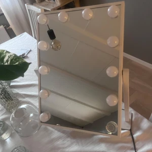 Sminkspegel med lampor - Snygg sminkspegel med inbyggda lampor runt ramen. Perfekt för att få till den rätta belysningen vid sminkning eller styling. Spegeln har en stilren design och passar bra på sminkbordet eller i sovrummet. Tryck ej på köp nu utan du får hämta den hemma hos mig köpt för 999kr ny