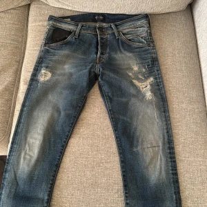 Blå jeans från Jack & Jones - Snygga blå jeans från Jack & Jones med slitna detaljer och en cool, avslappnad look. De har en klassisk femficksdesign och en bekväm passform. Perfekta för en casual stil.