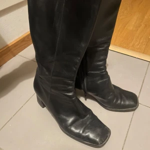 Svarta skinn boots - Snygga svarta stövlar i skinn med en bekväm klack och dragkedja på sidan. Perfekta för både vardag och speciella tillfällen. De har en klassisk design med en fyrkantig tå. Skriv om ni har frågor!