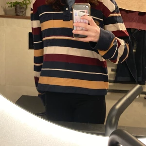 Randig pikétröja från Bon'A Parte - Säljer en randig pikétröja från Bon'A Parte i storlek XXL men den är omsydd så skulle säga att den är storlek L nu. Går mycket bra att använda som oversized. Tröjan har ett klassiskt mönster i marinblått, vinrött, beige och senapsgult. Den har långa ärmar och en knappslå vid halsen. Perfekt för en avslappnad stil.