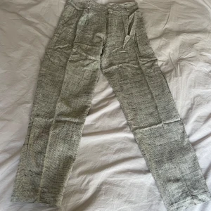 Grå byxor i polyester och bomull - Säljer ett par vintage grå byxor i en mix av polyester & bomull. De har en rak passform. Perfekta för en vardagsbruk. Byxorna har en diskret mönstring som ger dem lite extra karaktär. Storlek 31, som motsvarar storlek s/m.