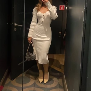 Stickad klänning med guldknappar  - Stickad klänning med guldknappar och lite lätt puffärm i midilängd. Storlek XS