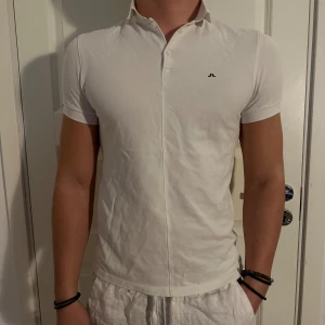 Vit Kortärmad Pikétröja från J.Lindeberg - Säljer en stilren vit pikétröja från J.Lindeberg i storlek S. Tröjan är kortärmad och har en klassisk krage med knappar. Tröjan är i väldigt bra skick! Storlek S. Modellen är 182 cm och väger 75 kg. Pris går att diskuteras!