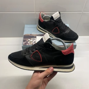 Philippe Model skor - Hej 👋 säljer nu ett par snygga svarta sneakers från Philippe Model med röda detaljer och snörning. Storlek: 42. I mycket bra skick. Skriv privat vid frågor eller funderingar😊