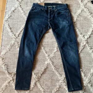 Dondup jeans - Snygga mörkblå jeans med kontrastsömmar och klassisk femficksdesign. Jeansen har en knappgylf och är tillverkade i ett slitstarkt denimtyg. Perfekta för en avslappnad stil. Använda men ändå i fint skick skulle säga 7,5/10. De sitter skinny/slim och är lite små i storleken så jag tror att de även passar 31 och 30, nypris ~ 4000kr. Tar bud. Skriv över frågor och funderingar. 