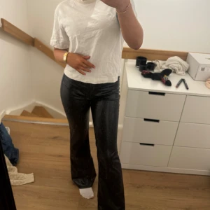 Svarta skinnbyxor - Passar s ,ENDAST PROVADE Snygga svarta skinnbyxor med medel midja och bootcat ben. Perfekta för en stilren look. Byxorna har dragkedja och knappar framtill.