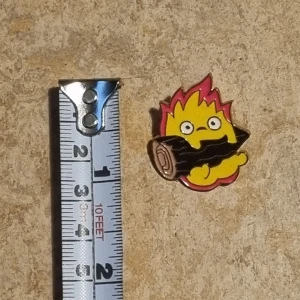 Färgglad eldformad pin, calcifer, ghibli studios - En liten och färgglad pin i form av en eld med ett ansikte, hållandes en vedklabb. Perfekt för att sätta på väskan eller jackan för en unik touch. Ghibli studios Calcifer.