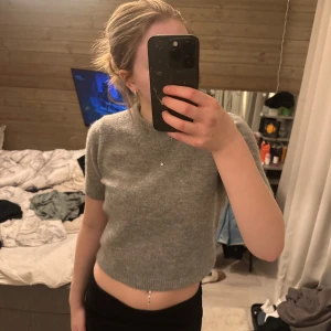 Grå stickad kortärmad tröja - Säljer en stilren grå stickad tröja med korta ärmar. Tröjan är croppad och har en ribbad kant vid ärmslut och nederkant. Den är från Zara och har tjockt material, få använd och är i bra skick! ‼️kan gå ner i pris vid snabb affär‼️