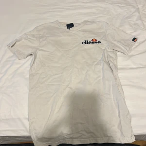 Vit t-shirt från Ellesse - Säljer en klassisk vit t-shirt från Ellesse med logotyp på bröstet. Den är kortärmad och har en rund halsringning. Perfekt för en avslappnad stil.