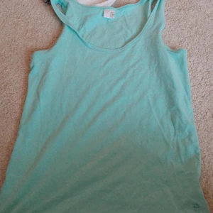 Turkos ärmlös linnetopp - Säljer en fräsch turkos ärmlös linnetopp i storlek 42. Perfekt för varma sommardagar eller som ett lager under en jacka. Toppen är tillverkad i ett mjukt och bekvämt material.