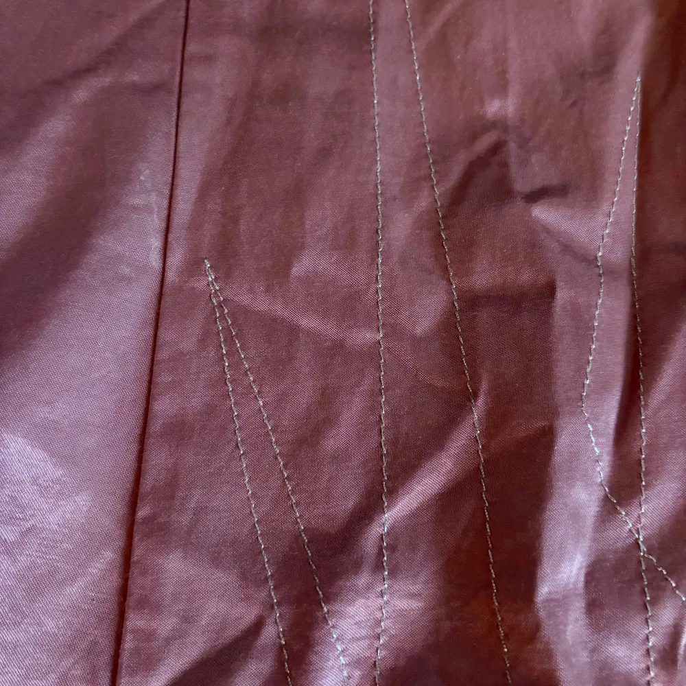 Snygg rosa kjol från Vero Moda i en klassisk A-linjeform. Kjolen har en diskret dragkedja på sidan och är perfekt för en stilren look. Materialet ger en lätt glansig finish.. Hameet.