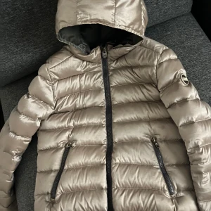 Colmar dunjacka stl XS-S (stl42) - Colmar dunjacka italiensk stl 42 vilket motsvarar XS-S. Färg beige shine med grått foder. Hittar inga fel. Perfekt för höst/vinter/vår.