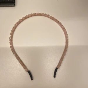 Rosa glittrigt hårband - Snyggt rosa hårband med glittriga detaljer. Perfekt för att ge en extra touch till din frisyr. Hårbandet har en elastisk del för bättre passform.
