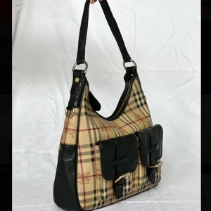 Rutig axelväska från Burberry - ❗️TRYCK INTE PÅ KÖP DIREKT ❗️. Hej! Säljer nu min fina retro burberry väska som är väldigt unik och svår att få tag på, då den inte finns att köpa längre. Väskan är äkta. Måtten är 38x33x9                                              Vid frågor och mer bilder är det bara att höra av sig !                                                                             ✨Vid fler intresserade blir det högst budande!✨ Köp direkt för 10 450kr, 