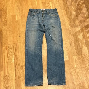 Blå Levis 501 jeans - Klassiska blå Levis 501 jeans i 100% bomull. De har en rak passform och är perfekta för en avslappnad stil. Tillverkade i Mexiko, dessa jeans är tidlösa och hållbara.