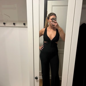 Festlig jumpsuit  - Snygg och sexig byxdress i bekvämt material. Endast använd en gång! Storlek 36 men är väldigt stretchig så kan motsvara storlek 38 också. Benen är vida och är en ganska lång modell ( jag är 178cm lång )