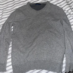 Grå ulltröja från Polo Ralph Lauren - Säljer en stilren grå ulltröja från Polo Ralph Lauren. Tröjan har en klassisk rund hals och är perfekt för kyligare dagar. Den är tillverkad av italiensk ull och har långa ärmar.