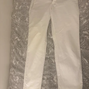 Vita kostymbyxor från Tommy Hilfiger - Snygga vita kostymbyxor från Tommy Hilfiger med en elegant design. Byxorna har en rak passform och är tillverkade i ett bekvämt material. Perfekta för en stilren look.