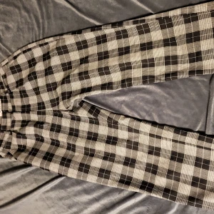 Rutig byxa från NA-KD - Snygga svartvita rutiga byxor från NA-KD. Perfekta för en stilren look med normal passform och hög midja. Tillverkade i ett bekvämt material som passar både till vardags och mer uppklädda tillfällen.