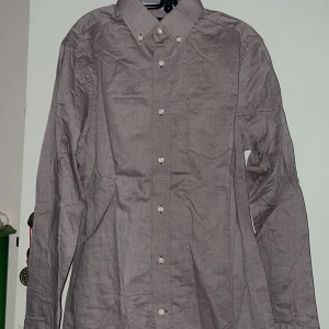 Brun skjorta från Riley - Säljer en stilren brun skjorta från Riley i slim fit. Skjortan har långa ärmar och knappar framtill samt vid kragen. Perfekt för en elegant look.