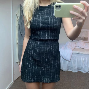 Svart kortklänning med mönster - Snygg svart kortklänning med ett subtilt randigt mönster. Klänningen är perfekt för festliga tillfällen!