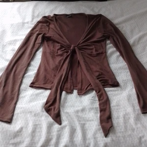 Brun långärmad topp med knyt - Säljer en brun långärmad topp med knyt framtill. Perfekt för lager-på-lager och en stilren look. Passar bra till både jeans och kjol.